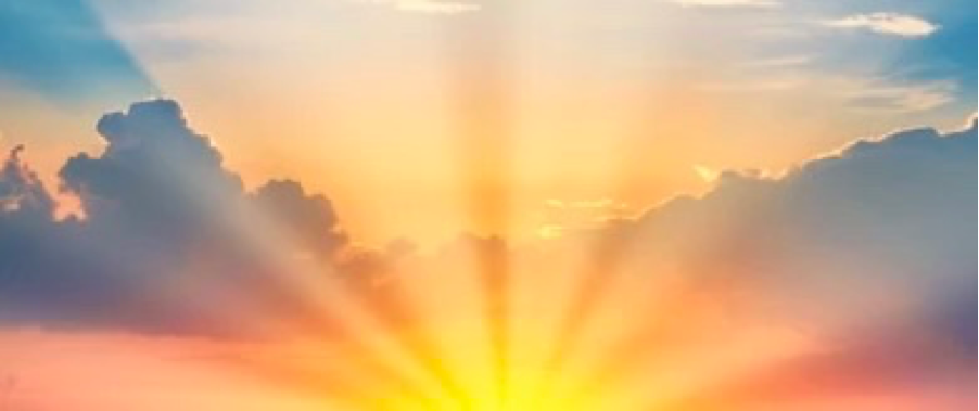 die unter zwei dunklen Wolken aufgehende Sonne lässt den Himmel in dunkelorange bis gelborangen Tönen erstrahlen